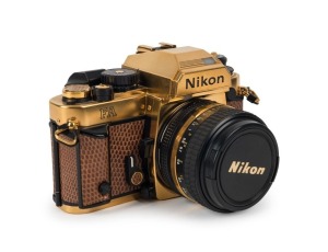 NIPPON KOGAKU: 1984 Nikon FA 35mm SLR camera [#2002664], with Nikkor 50mm f1.4 lens [#5509321] and original lens cap. Voted 'European Camera of the Year 1984', this Nikon FA is gold-plated and covered in brown lizard skin, and presented in wooden maker's 