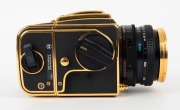 HASSELBLAD: 1985 Hasselblad 2000FC/M '100 Years in Photography' limited-edition medium-format SLR camera [#RI 1520698 & #RI 3264751] in black and gold, with Planar 80mm f2.8 lens [#5872721]. Bears a plaque indicating that this camera is number 227 of 1500 - 4