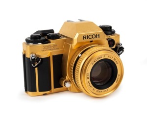 RIKEN OPTICAL: Circa 1986 special-edition gold-plated XR-P camera [#80 203257] with Rikenon 50mm f1.7 lens, in maker's box with certificate of authenticity, instruction booklet, and wrist strap. Produced to commemorate 50 years of camera production.