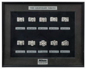 NIPPON KOGAKU: Framed commemorative display titled 'The Legendary Nikons' featuring an array of embossed pins depicting various iconic Nikon cameras from throughout the history of the company, such as the 1948 Nikon I, the 1959 Nikon F, and the 1988 Nikon