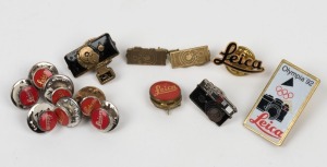 LEITZ: Various Leica-branded metal badges and lapel pins, including eight Leica 'Red Dot' logo pins, and one Leica 'Olympia 92' badge, among others. (14 items)