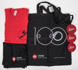 LEITZ: Five Leica-branded promotional items, including one red shirt, two cloth carry bags, and three 'Red Dot' sew-on patches. (5 items)