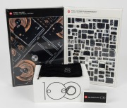 LEITZ: Five '100 Years of Leica Photography' commemorative items, including two sealed jigsaw puzzles, one animation flipbook, one point of sale camera display, and one felt pouch.&nbsp;(5 items)