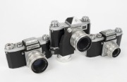 KAMERA-WERKST&Auml;TTEN: Three 1950s&nbsp;SLR cameras - one Praktica FX with Tessar&nbsp;50mm f2.8 lens [#4779778] and spring-driven motor transport attachment, one Praktica FX2 with Biotar&nbsp;58mm f2 lens [#4419090], and one Praktica FX2 with Trioplan&nbsp;50mm f2.9 lens [#168
