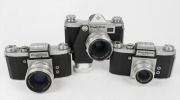 KAMERA-WERKST&Auml;TTEN: Three 1950s&nbsp;SLR cameras - one Praktica FX with Tessar&nbsp;50mm f2.8 lens [#4779778] and spring-driven motor transport attachment, one Praktica FX2 with Biotar&nbsp;58mm f2 lens [#4419090], and one Praktica FX2 with Trioplan&nbsp;50mm f2.9 lens [#168 - 2
