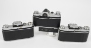 KAMERA-WERKST&Auml;TTEN: Three 1950s&nbsp;SLR cameras - one Praktica FX with Tessar&nbsp;50mm f2.8 lens [#4779778] and spring-driven motor transport attachment, one Praktica FX2 with Biotar&nbsp;58mm f2 lens [#4419090], and one Praktica FX2 with Trioplan&nbsp;50mm f2.9 lens [#168 - 3