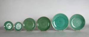 A graduated set of six green glazed saucer dishes, 18th/19th century, each with a blue seal mark to base, ranging from 14cm to 26cm diameter
