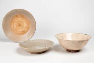 Two Southern Chinese dishes and a bowl, each with a crazed buff coloured glaze, 18th/19th century, 27cm, 23cm and 22.5cm diameter