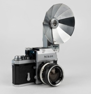 NIPPON KOGAKU: Nikon F Photomic T SLR camera [#6766494], circa 1965, with Nikkor-S Auto 35mm f2.8 wide-angle lens [#371067], Photomic T metering prism, and Nikon F BC-7 flash unit attachment.