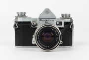 KAMERA-WERKST&Auml;TTEN: Circa 1958 Praktina IIa SLR camera [#107 565] with Flexon 50mm f2 lens {#5471997] and front lens cap. Together with maker's box, leather body casing, lens hood, rapid-wind lever accessory, and instruction booklet. - 3