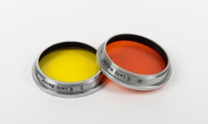 LEITZ: Two circa 1939 Leica lens filters - one GCOOL medium yellow and one GDOOK orange in original plastic case. (2 items)