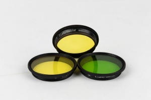 LEITZ: Three circa 1939 Leica lens filters - one GBWOO light yellow, one GCOOL medium yellow, and one GILOO graduated green. (3 items)