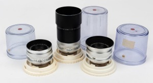 KODAK: Three circa 1960s lenses in clear plastic domes with lock-in plastic bases - one Curtagon 28mm f4 [#11594871], one Retina-Curtagon 28mm f4 [#8854927], and one Tele-Xenar 135mm f4 [#11571286] with metal lens hood. (3 lenses)