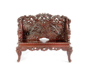 A Japanese lacquered hardwood couch, Meiji Period, 1868-1912, carved in relief with dragon arms and dragon and phoenix design on the back. 120cm high, 142cm wide and 58cm deep