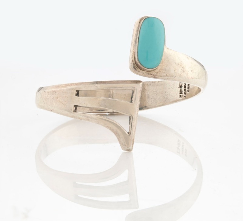 A Mexican sterling silver Modernist bangle, set with a cabochon turquoise specimen, stamped "Mexico, 925", ​​​​​​​6.5cm wide, 50 grams