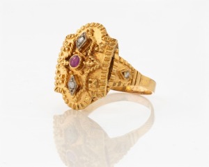 An Indian 18ct yellow gold ring, set with a ruby and two diamonds, stamped "750", ​​​​​​​11.2 grams
