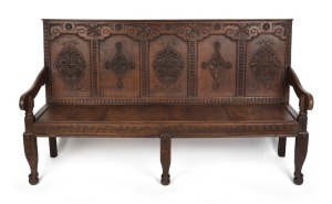 An antique English oak settle with carved panel back, 18th/19th century, 102cm high, 177cm across the arms