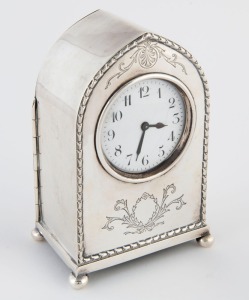 An antique sterling silver cased lancet top bedside timepiece with engraved bell flower decoration, time only French movement with platform escapement, one piece enamel dial with Arabic numerals, circa 1900, 16cm high