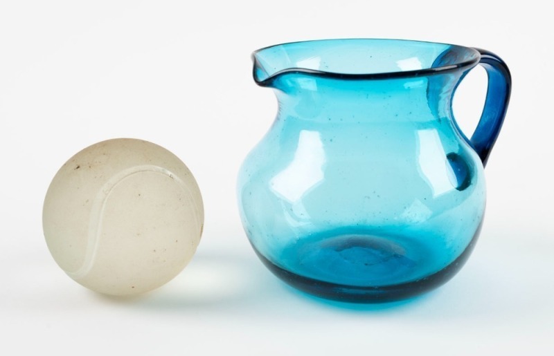 An unusual Murano glass tennis ball ornament with original circular label "Made in Murano, Italy"; together with an antique blue glass water jug, 19th and 20th century, (2 items), the jug 10cm high