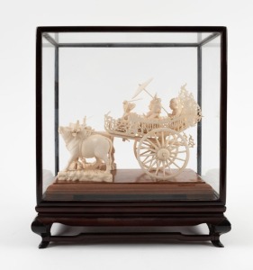 A Burmese carved ivory wagon sculpture, housed in timber and glass case, mid 20th century, the case 30cm high overall