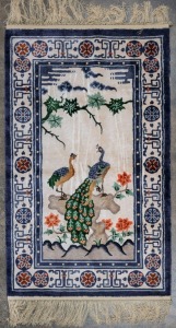 A hand-knotted Chinese silk rug with peacocks and flowers, 160 x 94cm.