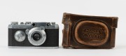 CANON: Circa 1937 HANSA rangefinder camera [#1082] with Nikkor 50mm f3.5 collapsible lens [#50712], metal lens cap, and original Canon HANSA ERC with straps. Featuring pop-up viewfinder, base plate with number 2743, and 'HANSA' engraving on top plate. - 2