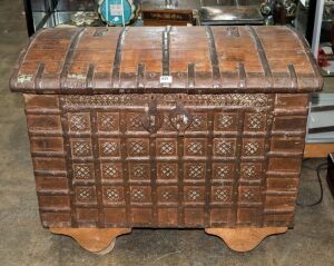 An antique Indo-Portuguese teak domed top dowry chest with iron strapping, 19th century, later wheels added, 79cm high, 97cm wide, 56cm deep