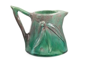 HARVEY SCHOOL green glazed pottery jug with burgundy highlights adorned with gumnuts and leaves, incised monogram to base "T.E.", 13cm high