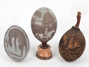 Two carved emu eggs (one mounted on mulga wood stand), and a carved boab nut, 20th century, (3 items), the largest 20.5cm high overall