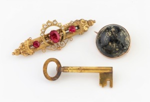 Three antique gold brooches comprising of a circular polished stone example mounted in rose gold by ROWLAND, a yellow gold key brooch stamped "T.J.J. & SON", and a WILLIS & SONS (attributed) yellow gold bar brooch with red stones and seed pearls (marks il