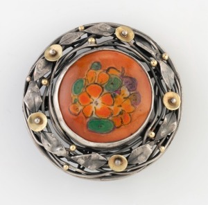 RHODA WAGER (attributed) circular silver brooch with gold highlights, set with a hand-painted floral porcelain panel signed "A.V." on the reverse. Purported to be the work of artist AMY VALE. 3.5cm wide