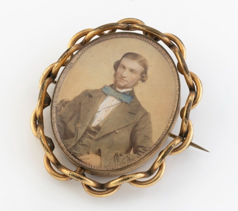 An antique pinchbeck swivel brooch with hand-coloured photo portrait of a young man, circa 1865, ​​​​​​​6.5cm high