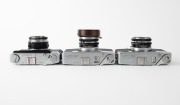 OLYMPUS: Three late 1950s rangefinder cameras - one Olympus Auto [#108199] with G. Zuiko 42mm f1.8 lens [#108605] and Olympus Auto metal lens hood, one Olympus Auto B [#102879] with E. Zuiko 42mm f2.8 lens [#102669], and one Olympus Auto Eye [#113895] wit - 4