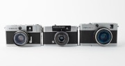 OLYMPUS: Three c. 1967 35mm half-frame cameras - one Pen-EM [#105763] with F. Zuiko 35mm f2 lens and Olympus 82C lens filter, one Pen Rapid-EE S [#100335] with D. Zuiko 30mm f2.8 lens and Olympus lens hood, and one Pen-EED [#251516] with F. Zuiko 32mm f1. - 2