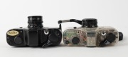 ASAHI KOGAKU: Two 110-cartridge SLR cameras - one c. 1979 Pentax Auto 110 with clear plastic body together with Pentax-110 24mm f2.8 lens [#1295813] and front lens cap, and one c. 1982 black-body Pentax Auto 110 Super with Pentax-110 24mm f2.8 lens [#1132 - 4