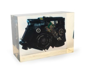 RIKEN: Circa 1980 point-of-sale display comprising one black Ricoh A-2 compact camera sealed in 16.5x7x11.5cm transparent plastic block. A publicity ploy that could not be effectively scaled due to excessive production costs.