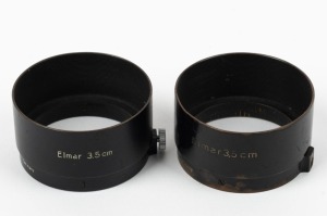 LEITZ: Two black c. 1936 FLQOO lens hoods, one with printed text, the other engraved. (2 items)