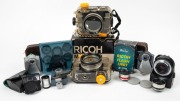 RIKEN: Eleven Ricoh accessories, some in maker's boxes - two Marine AD underwater housings, one AF Rikenon 50mm f2 lens, one aux telephoto lens for 45mm f2.8 with cap, one aux wide-angle lens for 45mm f2.8 with cap, one finder for aux lens, one TC-9 Tele