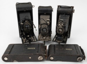 KODAK: Five c. late 1920s vertical-folding cameras - one No. 1A Pocket Kodak with shutter release cable, one No. 1 Kodak Jr., two No. 1-A Kodak Jr. models with varying shutter and lens details, and one No. 2C Pocket Kodak with shutter release cable. (5 ca
