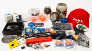 VARIOUS MANUFACTURERS: An accumulation of fifty promotional items, including multiple wristwatches, pens, balls, pin badges, tie clips, cups, lanyards, keyrings, etc., with brands such as Sony, Minolta, Konica, Agfa, Nikon, Olympus, and many others. (50 i