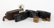 PURMA: Three c. 1937 Purma Special black Bakelite viewfinder cameras, one with lens cap, and one with lens cap, leather case, and instruction booklet, together with one lens hood in maker's box and two lens filters also&nbsp;in maker's boxes. (7 items)