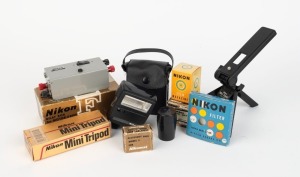 NIPPON KOGAKU: Seven Nikon camera accessories, most in maker's boxes with instruction booklets - one c. 1970 Nikon Relay Box for Motor Drive, one Nikon Mini Tripod for L35AF(2) and L35AD(2), one Model 2 Accessory Shoe for Nikomat, one NC Battery DN-1, one Nikon SB-4 Speed Light unit in leatherette pouch, one Nikon black metal Film Magazine, and one Nikon L39 52mm UV lens filter. (7 items)