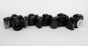 MINOLTA: Five black SLR camera bodies, one with lens and the others with plastic body caps - one Minolta Maxxum 7000 AF, one Minolta 7000 AF with AF Zoom 35-70mm f4 lens and lens hood, one additional Minolta 7000 AF, one Minolta Dynax 7xi, and one Minolta