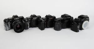 MINOLTA: Five black SLR camera bodies, one with lens and the others with plastic body caps - one Minolta Maxxum 7000 AF, one Minolta 7000 AF with AF Zoom 35-70mm f4 lens and lens hood, one additional Minolta 7000 AF, one Minolta Dynax 7xi, and one Minolta Dynax 600si Classic. (5 cameras)