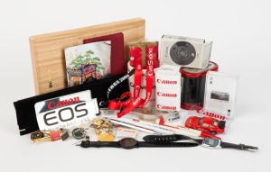 CANON: Thirty-seven Canon-branded items, including three wristwatches, one mug, one sealed wallet, three tie clips, five pins, three keyrings, one large Canon A-1 pencil sharpener, one sealed deck of playing cards featuring various camera models, one silk scarf from Canon Expo 2000 in wooden box, three napkin rings, one toy car, one nutcracker, and several other items. (37 items)
