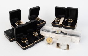 NIPPON KOGAKU: Thirteen Nikon-branded timepieces - nine c. 1993 black and gold quartz wristwatches with black snakeskin straps in black and gold presentation boxes, three black plastic wristwatches in transparent plastic cases, and one c. 2001 stainless steel 40mm diameter flip-top clock with gold face in Nikon-branded tin. (13 items)