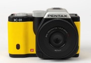 ASAHI KOGAKU: 2012 yellow-body Pentax K-01 digital camera [#4308569], with SMC Pentax-DA XS 40mm f2.8 lens, together with power pack. Camera base bears a print of the signature of Australian industrial designer Marc Newson, responsible for the camera's un - 2