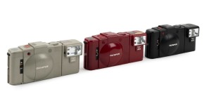 OLYMPUS: Three c. 1980 Olympus XA-2 compact cameras with D. Zuiko 35mm f3.5 lenses and A11 flash attachments - one in black [#5734551], one in cherry red [#5143858], and one in grey [#4785201]. (3 cameras)