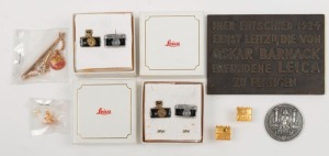 LEITZ: Eight metal commemorative items - Leica Historical Society of America lapel pin and tie clip, two LHSA pin badges, two boxed sets of two Leica camera pin badges, one 1983 medallion with reproduction of 1374 Wetzlar city sigil and text 'Ernst Leitz Wetzlar GmbH - Stadt Wetzlar - Bonn 24.XI.1983' verso, and one 12x8cm replica of Leitz administrative building plaque with text in German. (8 items)