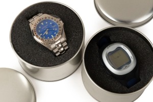 OLYMPUS: Two mint-condition Olympus Mju-branded quartz wristwatches in metal presentation tins, one in stainless steel with analogue face, and one in grey plastic and black rubber with digital face. (2 items)